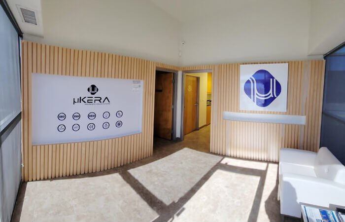 Modern lobby and reception area at uKERA USA featuring wood panel walls, corporate branding logo, a white sofa, and ISO certification badges.