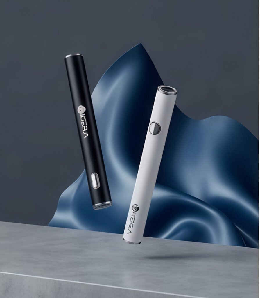 Two custom-branded uKERA 510-thread vape pen batteries in matte black and clean white hovering over a concrete platform with draped blue silk fabric backdrop.